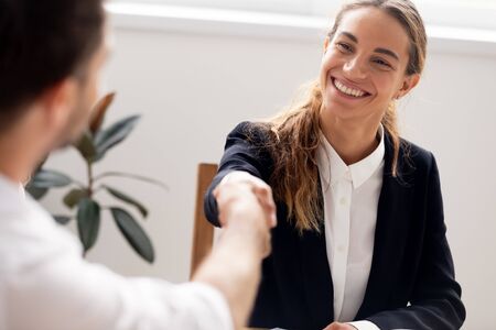 Smiling candidate shaking hand of hr manager, successful interview, business partners greeting each other, get job, satisfied client making insurance agreement or taking loan close upの写真素材