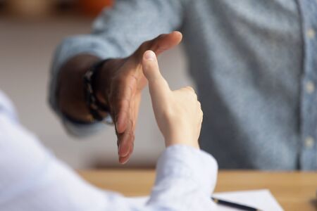 Close up African American businessman shaking hand of candidate at job interview, hiring process, greeting business partner at meeting, making agreement, signing contract, partnership conceptの写真素材