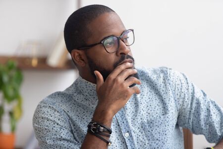 Pensive African American businessman pondering business strategy, serious employee thinking about...