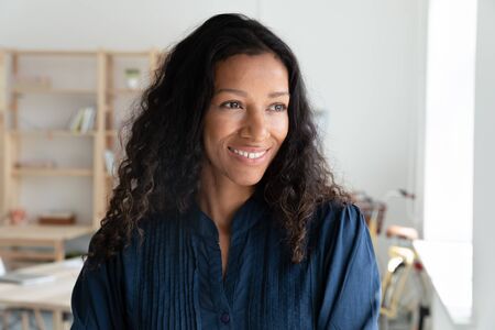 Smiling young female african american company employee looking away, planning workday, thinking of...