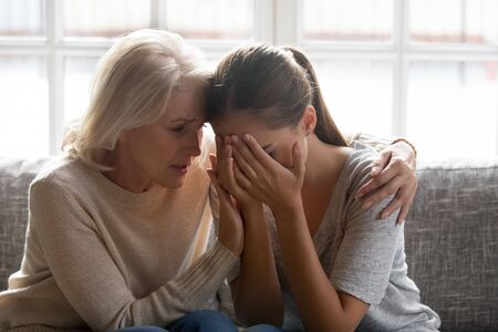 Upset carrying 60 years old mature mother cuddling hugging soothing crying desperate young grown up...