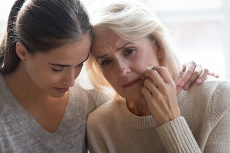 Close up head shot portrait young grown up worried daughter hugging frustrated crying middle aged...