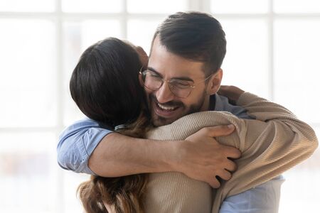 Woman hugs man close up view, smiling millennial couple embracing glad to see each other after long separation, greet at meeting expressing care and bonding, friendship and good warm relations conceptの写真素材