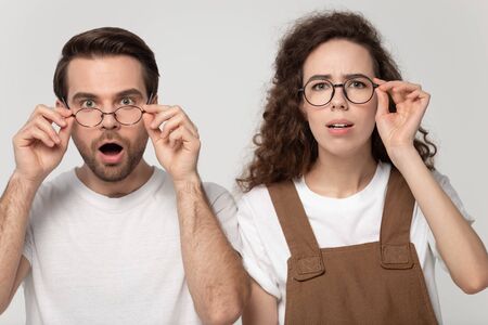 Shocked young friends or family couple dropping eyeglasses, feeling amazed head shot portrait....