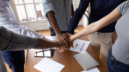 Close top view diverse employees put hands in stack showing support and unity, reach shared common goal together, multiracial people engaged in team building activity or training, concept of teamworkの写真素材