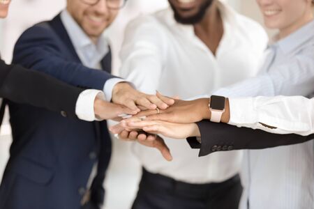 Diverse people with joined hands as a team. Happy engaged employee group mixed race putting hands together joining concept, close up view teambuilding training for motivating, result support teamwork.の写真素材
