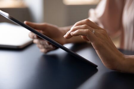 Side view close up young woman holding digital tablet, web surfing information online. Customer shopping in internet store via electronic gadget. Female designer using touchpad, drawing projects.の写真素材