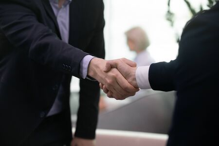 Close up of businessmen handshake getting acquainted greeting at office meeting, successful male...