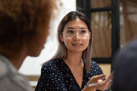 Serious Asian businesswoman wearing glasses talking at corporate briefing close up, sharing startup ideas with partners at negotiations, confident female team leader giving instructions at meetingの写真素材