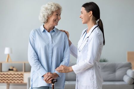 Caring young nurse support visit positive senior grandmother with walking stick at home, attentive female caregiver or doctor give help assist old lady patient in retirement house or clinic Caring young nurse support visit positive senior grandmother with walking stick at home, attentive female caregiver or doctor give help assist old lady patient in retirement house or clinic