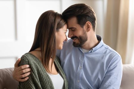 Head shot close up affectionate young man cuddling attractive smiling woman wife, touching...