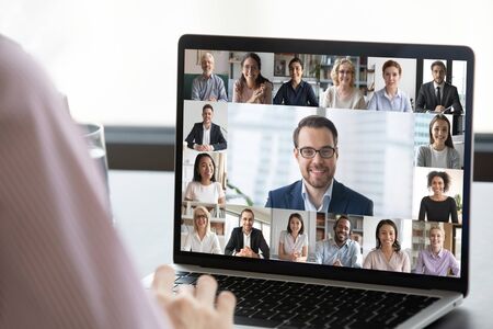 Close up of employee talk on video call on laptop with diverse colleagues, worker speak on web...