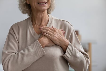 Close up middle aged happy woman thanking God with folded hands on heart, Grateful sincere smiling...