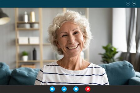 Head shot old granny sit on couch smiles looks at webcam enjoy pleasant distant conversation via pc and videoconference app, online consultation with doctor, chat with relatives adult children conceptの写真素材
