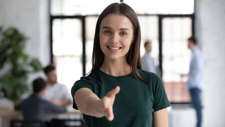 Headshot portrait of smiling young Caucasian businesswoman stretch hand welcome new employee at...