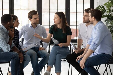 Concentrated diverse businesspeople sit in circle in office brainstorm discuss business ideas together, focused multiracial colleagues gather in boardroom consider plan at meeting, teamwork conceptの写真素材