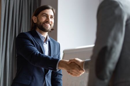 Smiling middle-aged businessman shake hand get acquainted greeting with male colleague at briefing, happy male employer handshake close deal make agreement at meeting in office, acquaintance conceptの写真素材