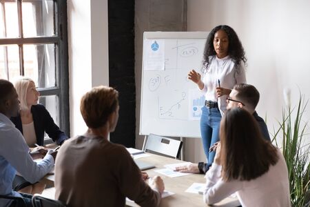 Young African American female coach or trainer talk to diverse colleagues present business project...