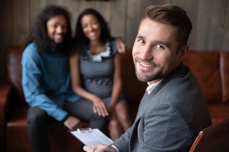 Smiling male Caucasian psychologist look at camera consult multiracial couple with relationships problems, successful confident man counselor or coach head family psychological session or therapyの写真素材
