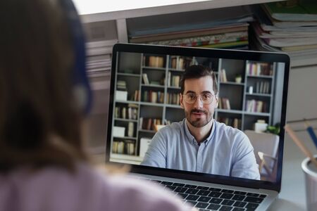 Back close up view of schoolgirl talk speak on video call with male teacher or tutor, teenage girl...