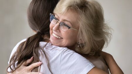 Close up happy 60 year old mother hugging and supporting adult daughter. Smiling mature grandmother embracing after long separation millennial granddaughter. Family warm love protection concept.の写真素材