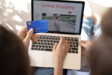 Close up top view of young people shopping online on laptop make payment with credit card, couple buyers pay on internet banking service system, buy or purchase on web from home, ecommerce conceptの写真素材