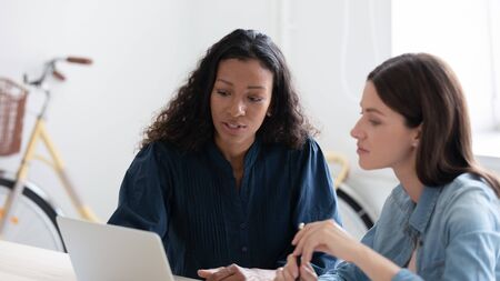 Confident young african american businesswoman tells new project to female mentor in coworking...