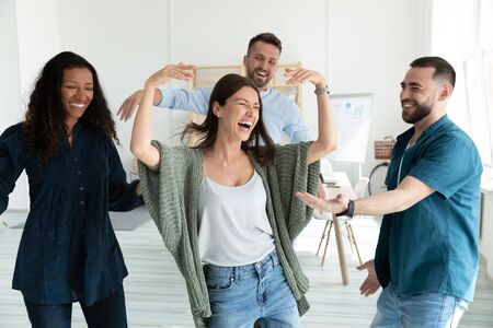 Smiling young businesswomen and businessmen dancing after successful deal. Diverse happy employee energy moving for break and relaxing. Motivated carefree multiracial business team.の写真素材