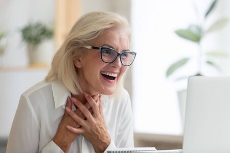 Surprised middle-aged businesswoman in glasses feel shocked read unexpected news online on laptop,...