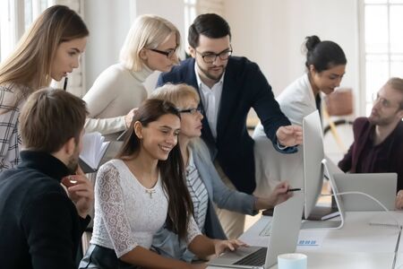 Smiling diverse business people working in small groups on project in modern office. Motivated...