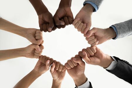 Close up bottom view diverse employees team holding fists in circle, expressing unity and power in...