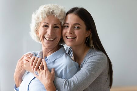 Older younger two different generations relatives women embracing posing smiling look at camera,...
