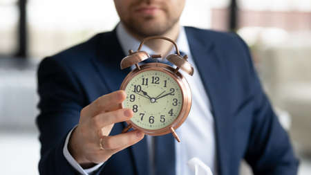 Crop close up of businessman hold show clock notify about deadline or time frame for new company project launch, male employer specify task startup limit, note about business meeting appointment