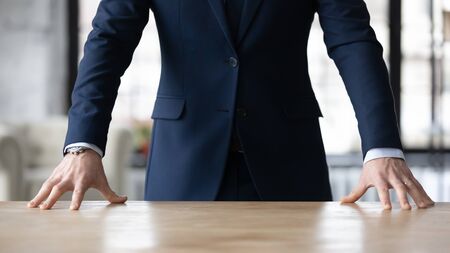 Crop close up of Caucasian businessman in formal suit stand at desk in office show confidence and power at workplace, hands of successful male leader or boss posing, leadership, success conceptの写真素材