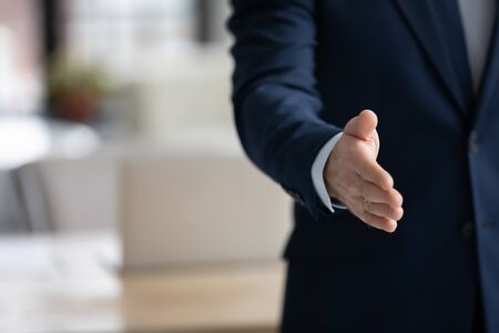Crop close up of Caucasian businessman stretch hand acquainted with partner or client in office,...