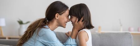 Horizontal photo banner for website header design loving mother seated on couch touching noses face...
