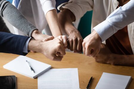 Close up image multi racial businesspeople associates putting fists together showing strong support synergy and business loyalty. Symbol of effective teamwork, trust reliability and motivation conceptの写真素材