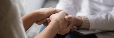 Psychologist in white coat holding hands of woman patient provide professional aid psychological...