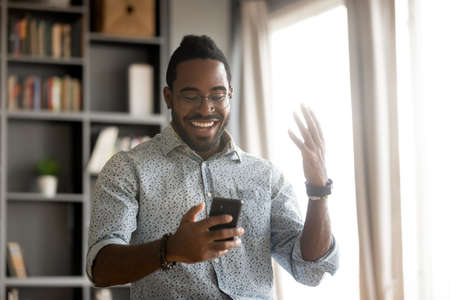 African man in casual clothes holds smartphone read message feels excited. Fast internet 5g...