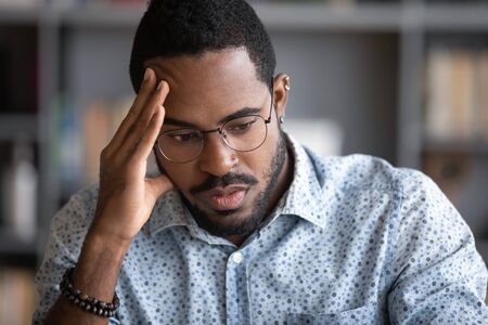 Close up African businessman think search problem solution feels concerned anxious. Guy student in...