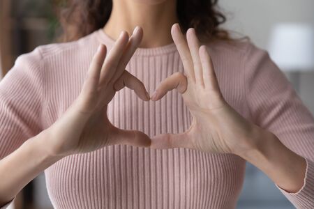 Close up young woman showing heart gesture with fingers, expressing love, support and care, gratitude, regular medical checkup promotion, cardiovascular diseases prevention, charity conceptの写真素材