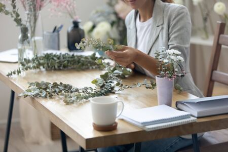 Crop close up of woman designer compose floral handmade house decorations on table, female florist or gardener make beautiful bouquets or compositions of flowers, interior decor, gardening conceptの写真素材
