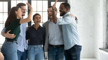 Five multi ethnic students or company employees accomplish project, exam pass, embracing feels...