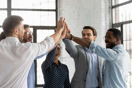 Multi racial millennial affiliates join hands giving high five celebrating common business success sales growth department promotion feels excited and motivated showing team spirit and synergy conceptの写真素材