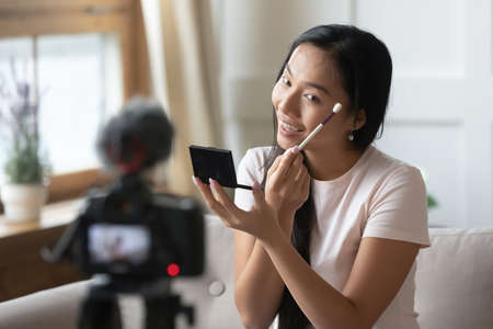 Beautiful young asian female blogger influencer sitting in front professional camera on stabilizer,...