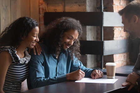 African couple sign listing contract with real estate broker sell own property. American spouses buy first house put signature on agreement legal document feels happy making deal with realtor conceptの写真素材