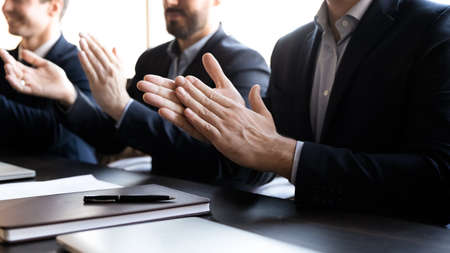 Close up group of businessmen in formal suit clapping hands at meeting, feeling excited about...