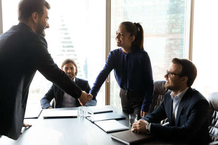 Happy young female human resources team leader shaking hands with smiling male job applicant,...