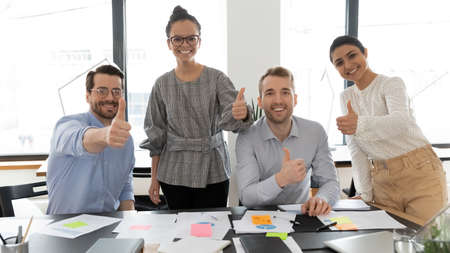 Portrait of smiling multiracial employees posing in office boardroom show thumb up recommend good quality service, happy diverse colleagues give recommendation to company, acknowledgement conceptの写真素材