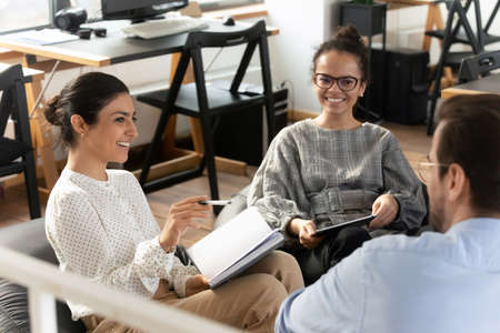 Smiling multiethnic young colleagues have fun take part in educational motivational training in...